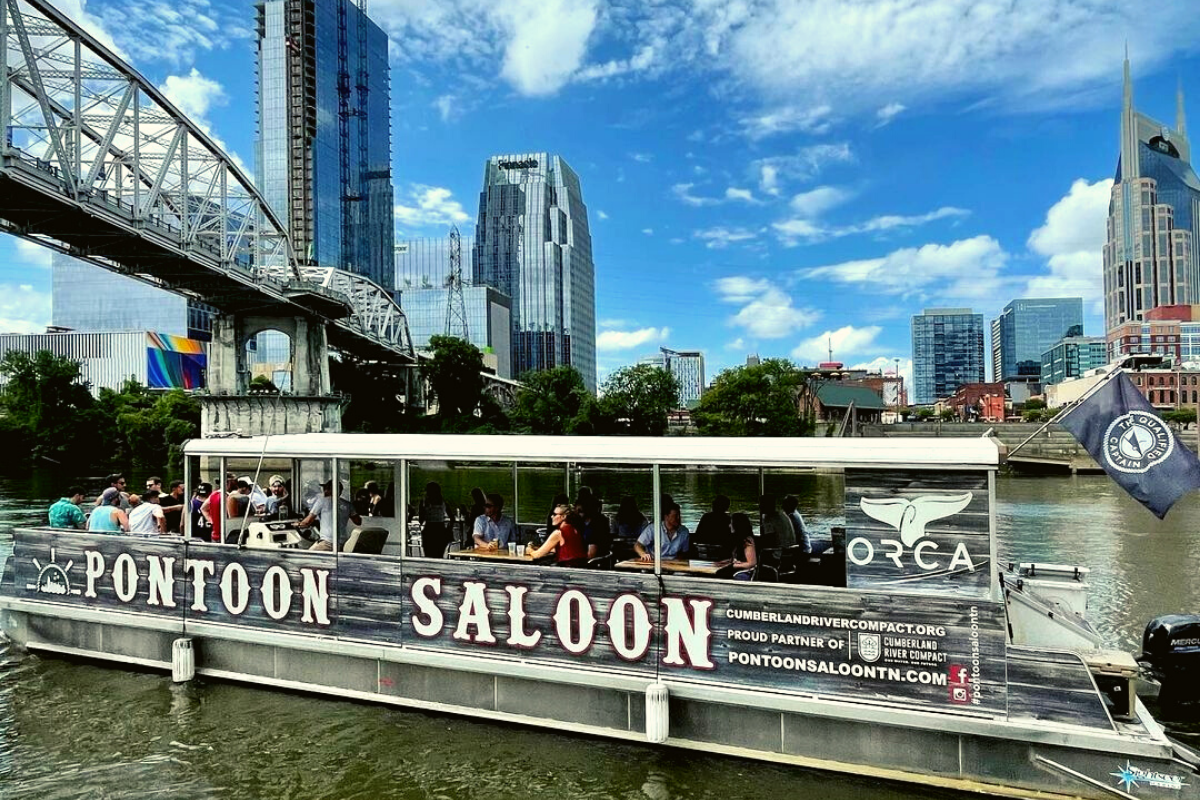 pontoon saloon cruising under a bridge on the river