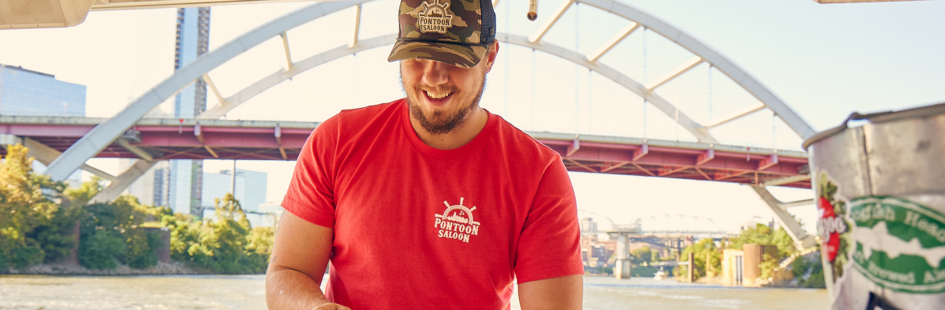 deckhand in a red shirt smiling with bridge behind him