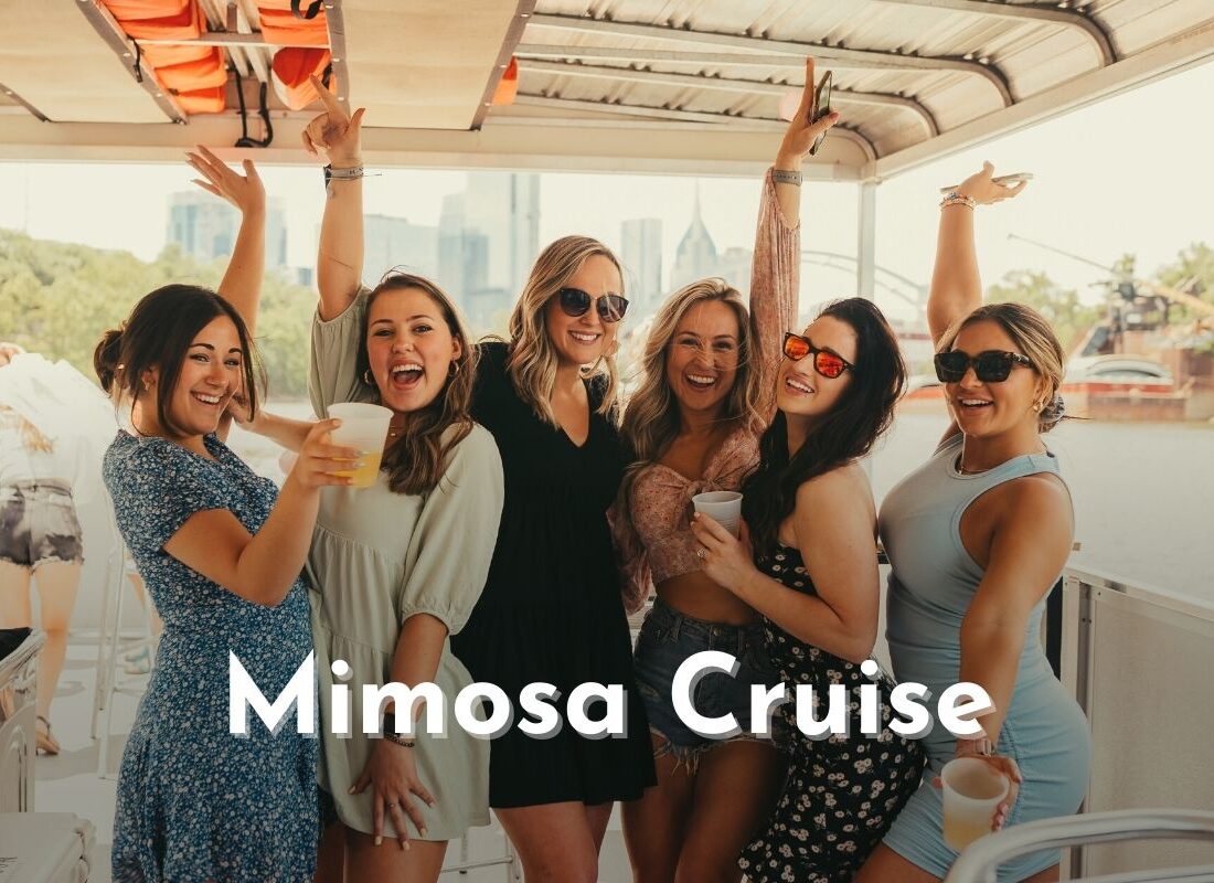 group of women with their hands in the air smiling on a mimosa cruise