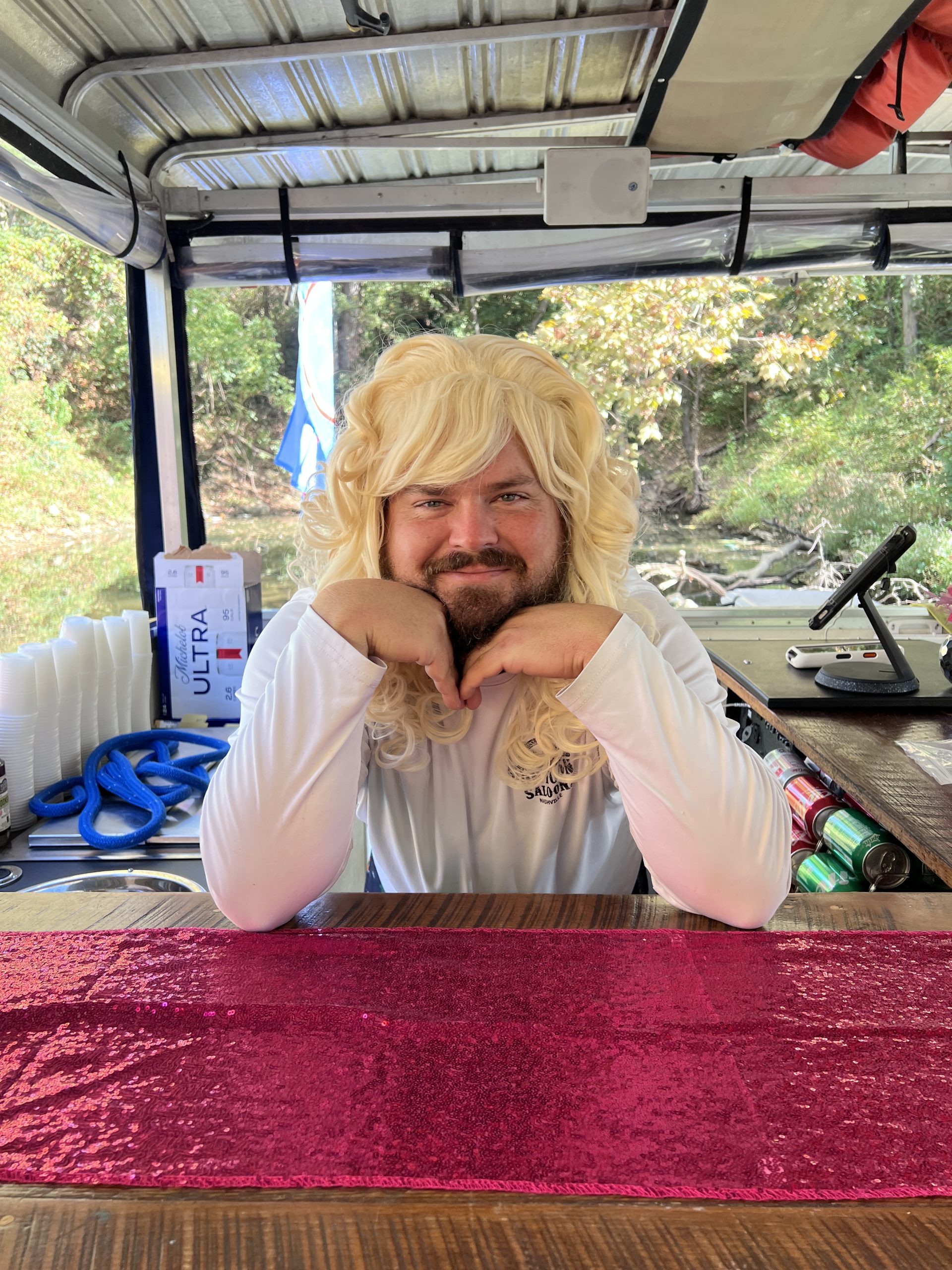 Guest in a blonde wig costume behind the bar on the Pontoon Saloon